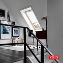 Salon avec fenêtre de toit VELUX. Une chaise de bureau devant un bureau. Logo VELUX.