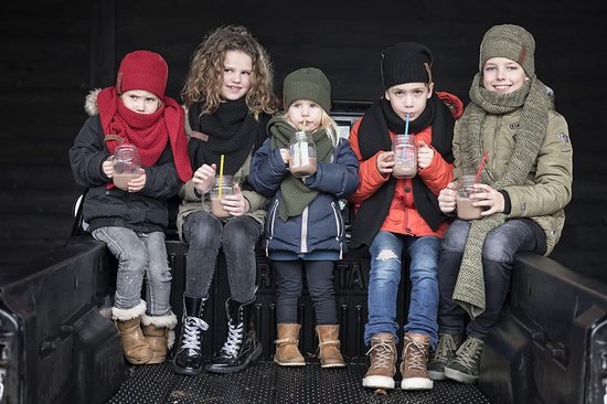 Vijf kinderen met winterkleding en mutsen, drinkend uit potjes met warme chocolademelk.
