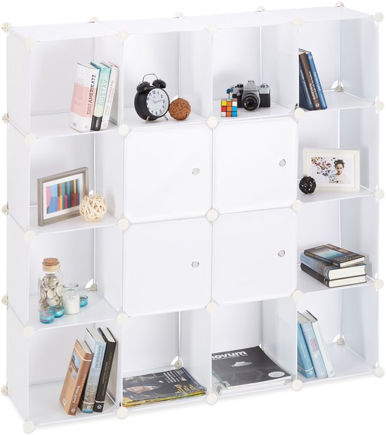 Witte vakkenkast van 16 vakken, met boeken, een camera en decoraties.