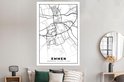 Affiche carte d'Emmen en noir et blanc, au-dessus d'un lit avec des coussins gris et verts.