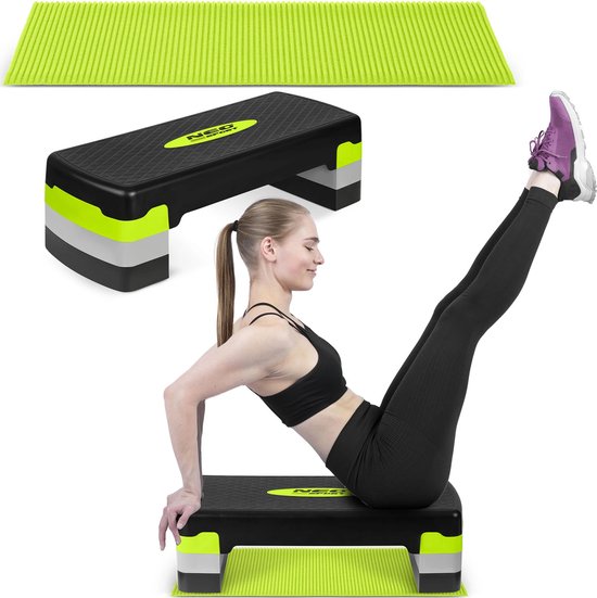 Vrouw maakt een buikspieroefening op een zwarte aerobic stepper met limegroene accenten en mat.