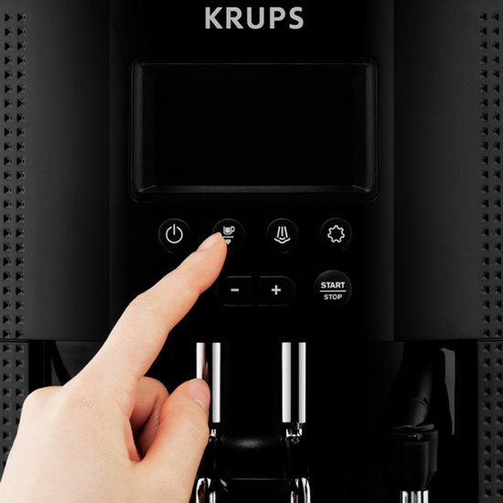 Vinger drukt op kopje-icoon op bedieningspaneel van zwarte Krups espressomachine.
