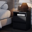 Une table de nuit noire avec deux tiroirs et un compartiment ouvert, à côté d'un lit.