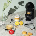 Zwarte Krups Dolce Gusto Piccolo XS koffiemachine in een keukenopstelling met koffie en koekjes.