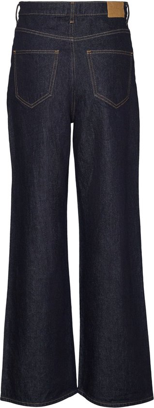 Achterkant van donkerblauwe wijde jeans met oranje stiksels en bruin leren label.