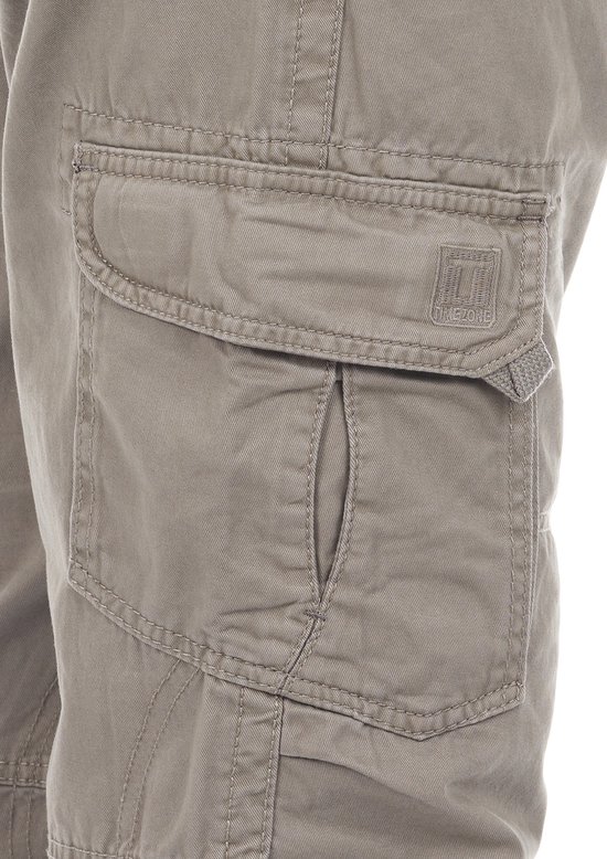 Close-up van de cargo zak op de grijze broek met 'TIMEZONE' logo.