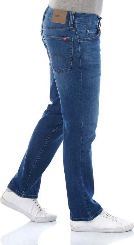 Man in rechte, blauwe Mustang spijkerbroek, grijs T-shirt en witte sneakers.
