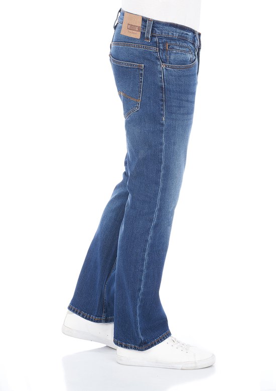 Zijkant van een blauwe denim jeans met bootcut pasvorm, gedragen met witte sneakers.
