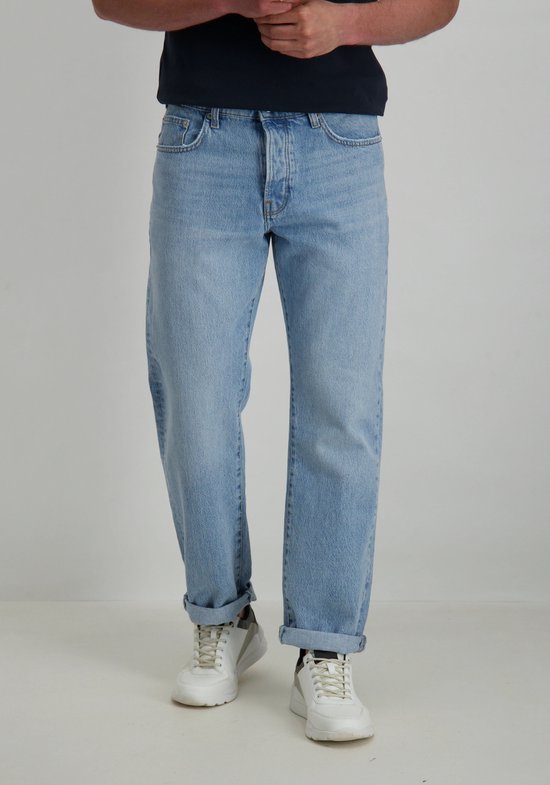 Man in lichtblauwe jeans met opgerolde broekspijpen.