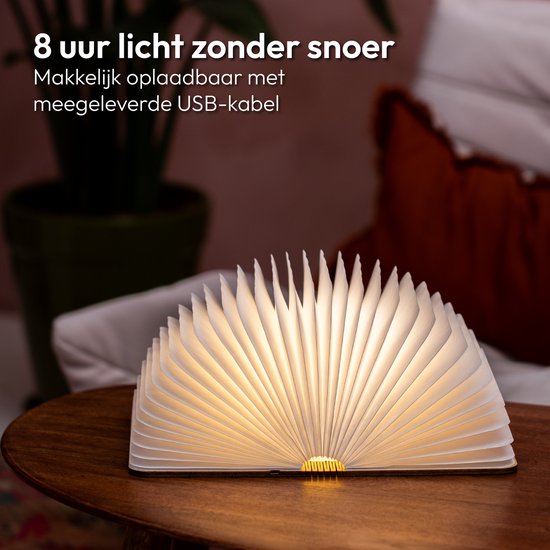 Lampe-livre avec couverture en bois, pliée ouverte avec des pages éclairées, sur une table.
