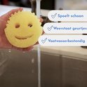 Gele Scrub Daddy spons met gezichtje, onder de kraan. Spoelt schoon, weerstaat geurtjes.