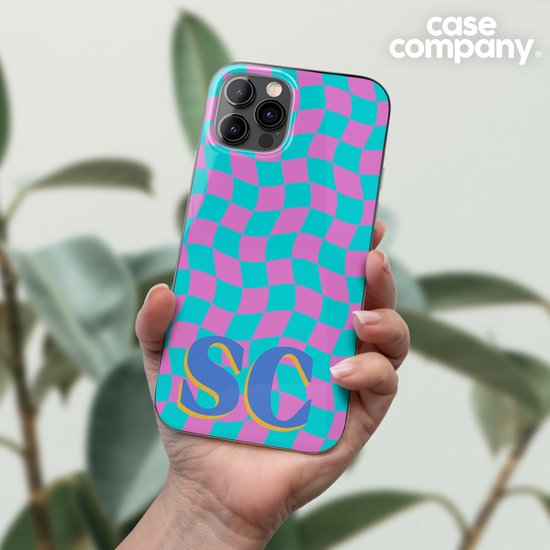 Hand houdt telefoonhoes vast met een cyaan en roze geruite golfpatroon en initialen SC.