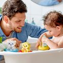 Een vader en baby spelen in bad met drijvende DUPLO dieren: een witte beer, gele eend en mintgroene nijlpaard. De baby speelt met de blauwe wolk.