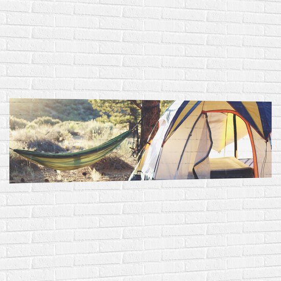 WallClassics - Muursticker - Hangmat bij Tent in Bos - 150x50 cm Foto op Muursticker