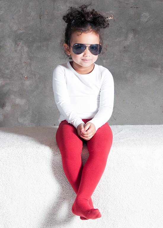 Meisje met krullend haar, witte longsleeve, rode maillot en zonnebril.