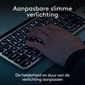 Main sur un clavier Logitech MX Keys S gris avec éclairage intelligent personnalisé.