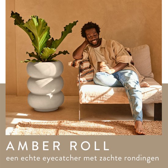 Grijze, gestapelde pot 'Amber Roll'. Man ontspant op bank ernaast.