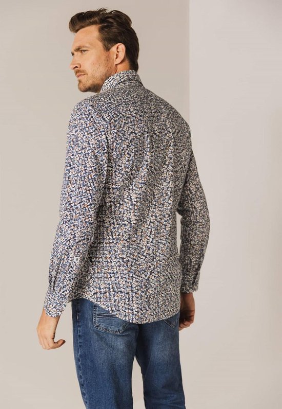 Man met een blauw-wit met bruine print overhemd en spijkerbroek, staand van achteren.