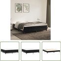 Zwart boxspringbed met witte matras, vierkante poten, gestoffeerde basis, in slaapkamer met planten en dekens.