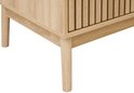 Detail van de poot en de zijkant van een licht houten tv-meubel met lamellen.