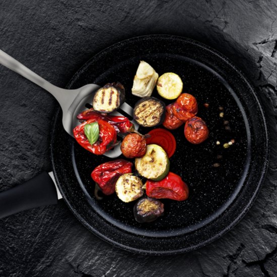 Gegrilde groenten, waaronder courgette, paprika en aubergine, op een spatel in een koekenpan.