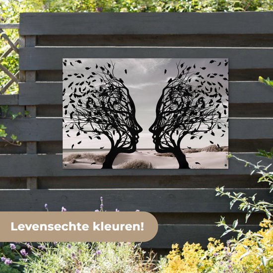Zwart silhouet van twee bomen met gezichtsprofielen die naar elkaar toe staan, op een schutting.