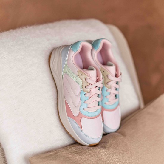 Paar roze Skechers sneakers met pastelkleurige accenten, rustend op kussens.