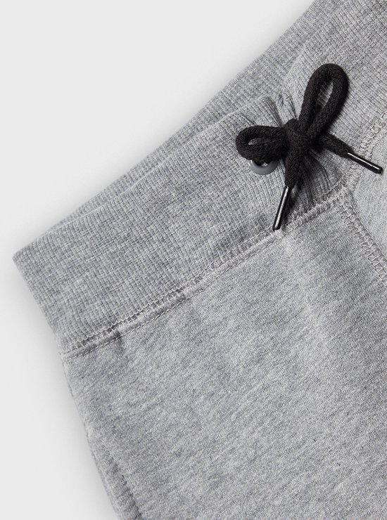 Detail van de tailleband en het trekkoord van een grijze joggingbroek.