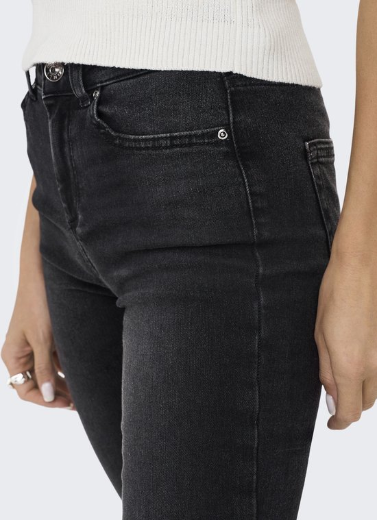 Close-up van de voorkant van een zwarte skinny jeans met een mid-waist model.