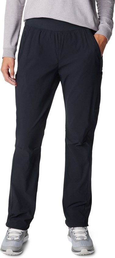 Femme portant un long pantalon d'extérieur noir et des baskets grises.