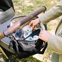 Mains remplissant un sac à langer noir avec des articles pour bébé.
