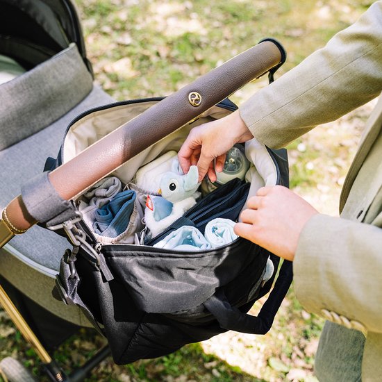 Mains remplissant un sac à langer noir avec des articles pour bébé.