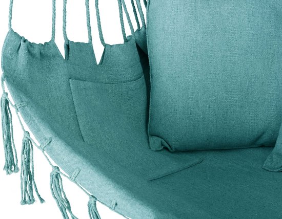 Close-up van turquoise hangstoel met opgestikte zak, kussen en franjes aan de onderrand.