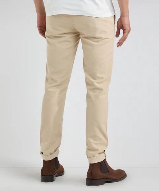 Man van achteren gezien in crèmekleurige chino broek van moleskin, met opgerolde broekspijpen en bruine laarzen.