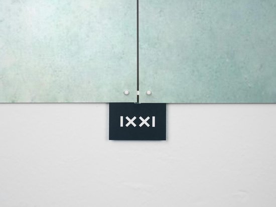 Une petite plaque bleu foncé avec les chiffres romains 'XXI', suspendue sous un panneau de verre aux détails vert pâle.