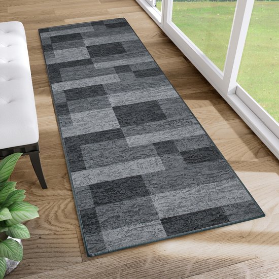 Tapis de sol gris à motif géométrique en blocs dans un salon près d'une fenêtre.