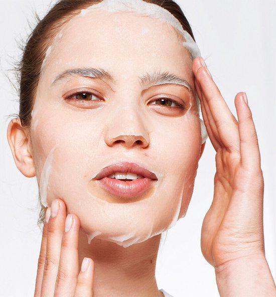 Vrouw met een nat Garnier SkinActive hydraterend gezichtsmasker op, terwijl ze het aanbrengt.