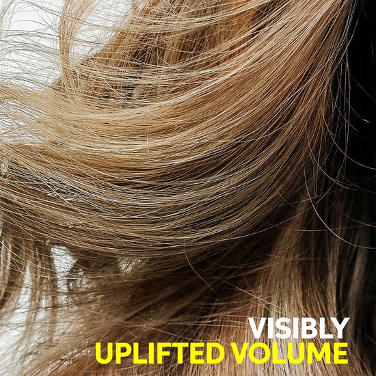 Close-up van lichtbruin haar dat volume krijgt met de tekst 'VISIBLY UPLIFTED VOLUME'.