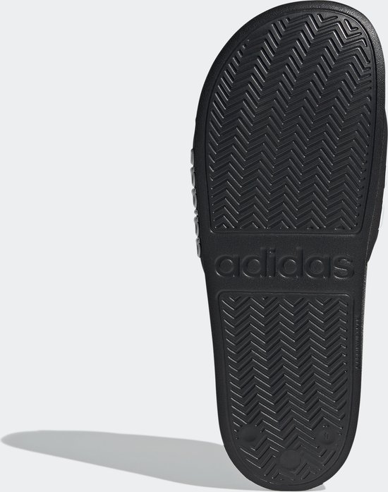 Semelle de tong Adidas noire avec motif à chevrons et logo.