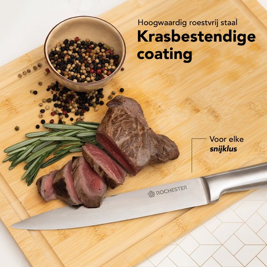 Een mes met krasbestendige coating snijdt een stuk vlees op een houten plank met rozemarijn en peperkorrels.