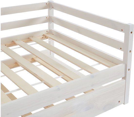 Detail van het witte houten bedframe met lattenbodem.