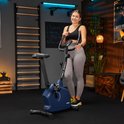 Vrouw in sportkleding poseert naast een marineblauwe hometrainer met 'TREX SPORT' logo.