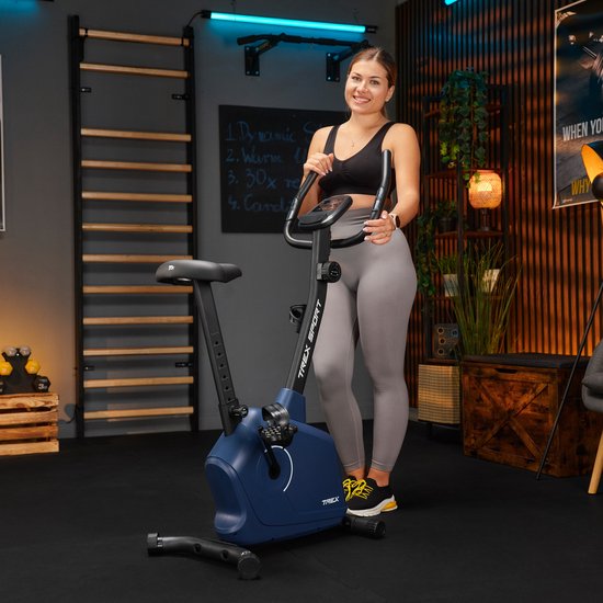 Vrouw in sportkleding poseert naast een marineblauwe hometrainer met 'TREX SPORT' logo.