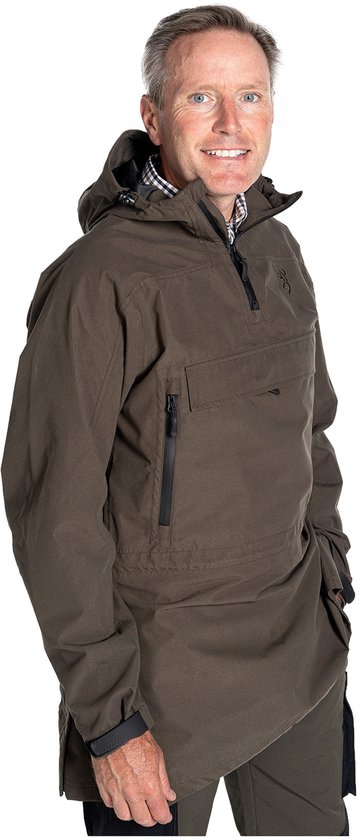 Homme aux cheveux poivre et sel, souriant, portant une longue veste anorak vert foncé à capuche, fermeture éclair ouverte et poches.