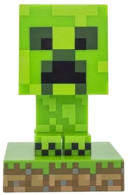 Een pixelachtige, felgroene Minecraft Creeper-lamp op een gras- en aarde-voetstuk.