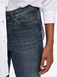 Gedetailleerde close-up van een donkerblauwe skinny jeans met een lichte wassing en koperkleurige details.