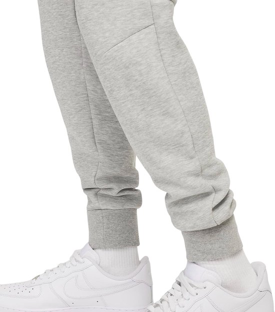 Onderlichaam van een man in een grijze Nike joggingbroek met witte sneakers.