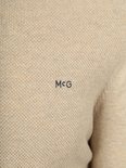 Beige trui met 'MCG' logo op de borst.