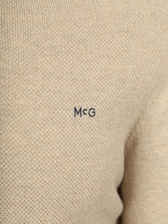 Beige trui met 'MCG' logo op de borst.