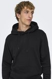 Man met blonde haren, close-up, draagt een zwarte hoodie met capuchon en touwtjes.